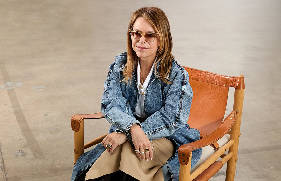 Woman wearing a watch, sitting on a chair, showcasing luxury timepieces.