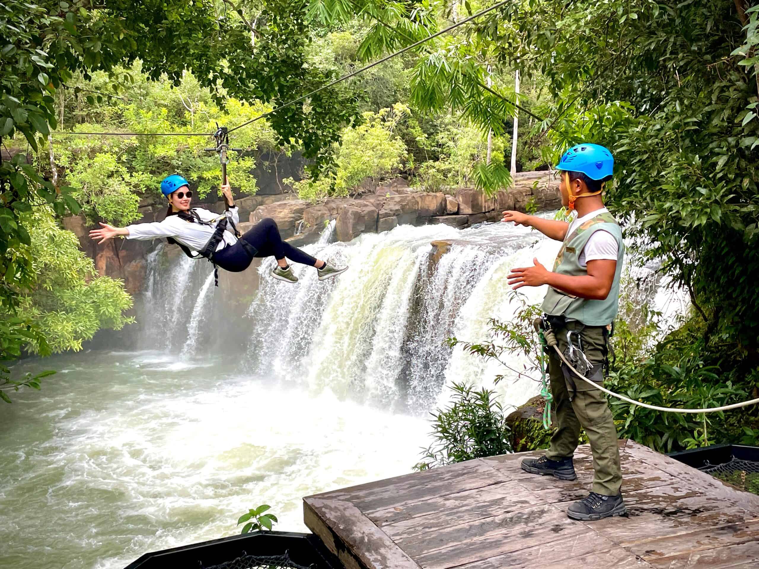 A woman ziplining over a waterfall