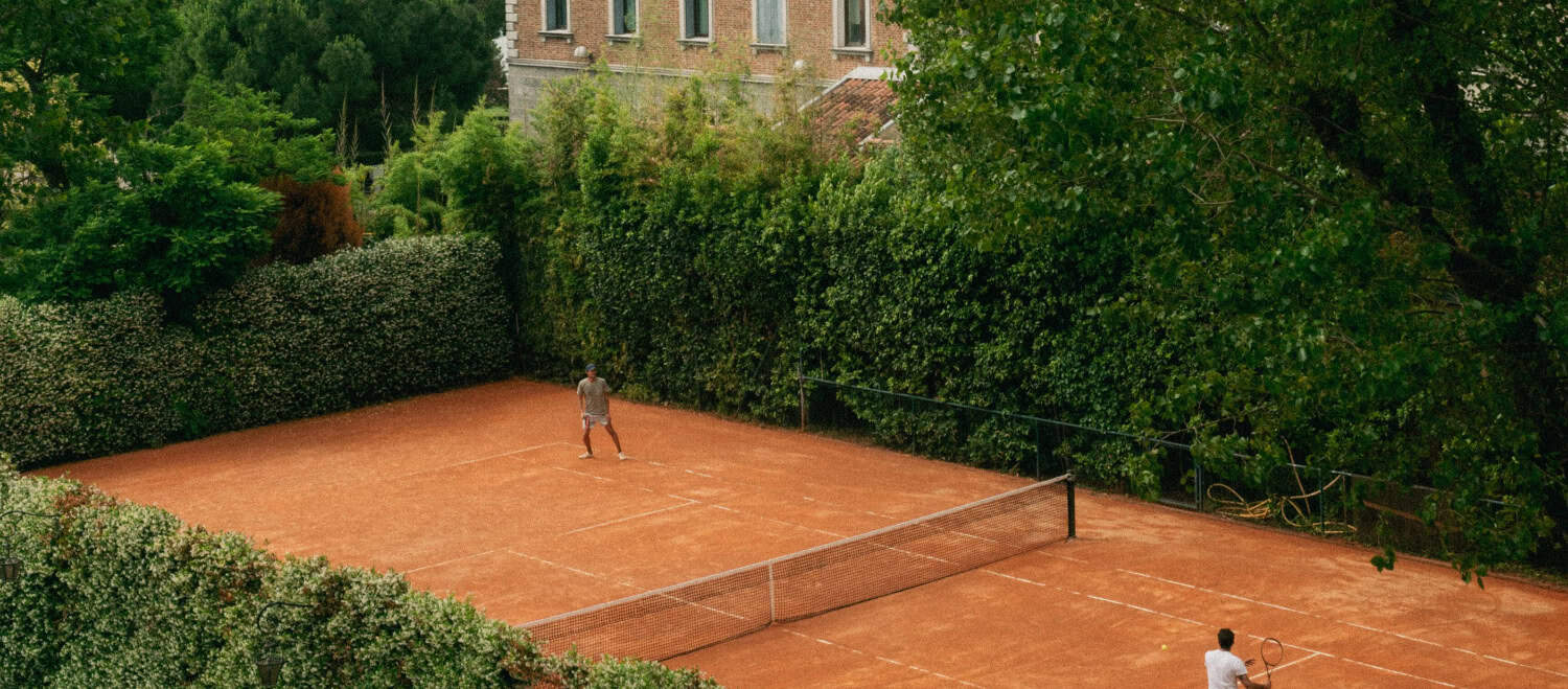 Tennis court in front of a regal manor.