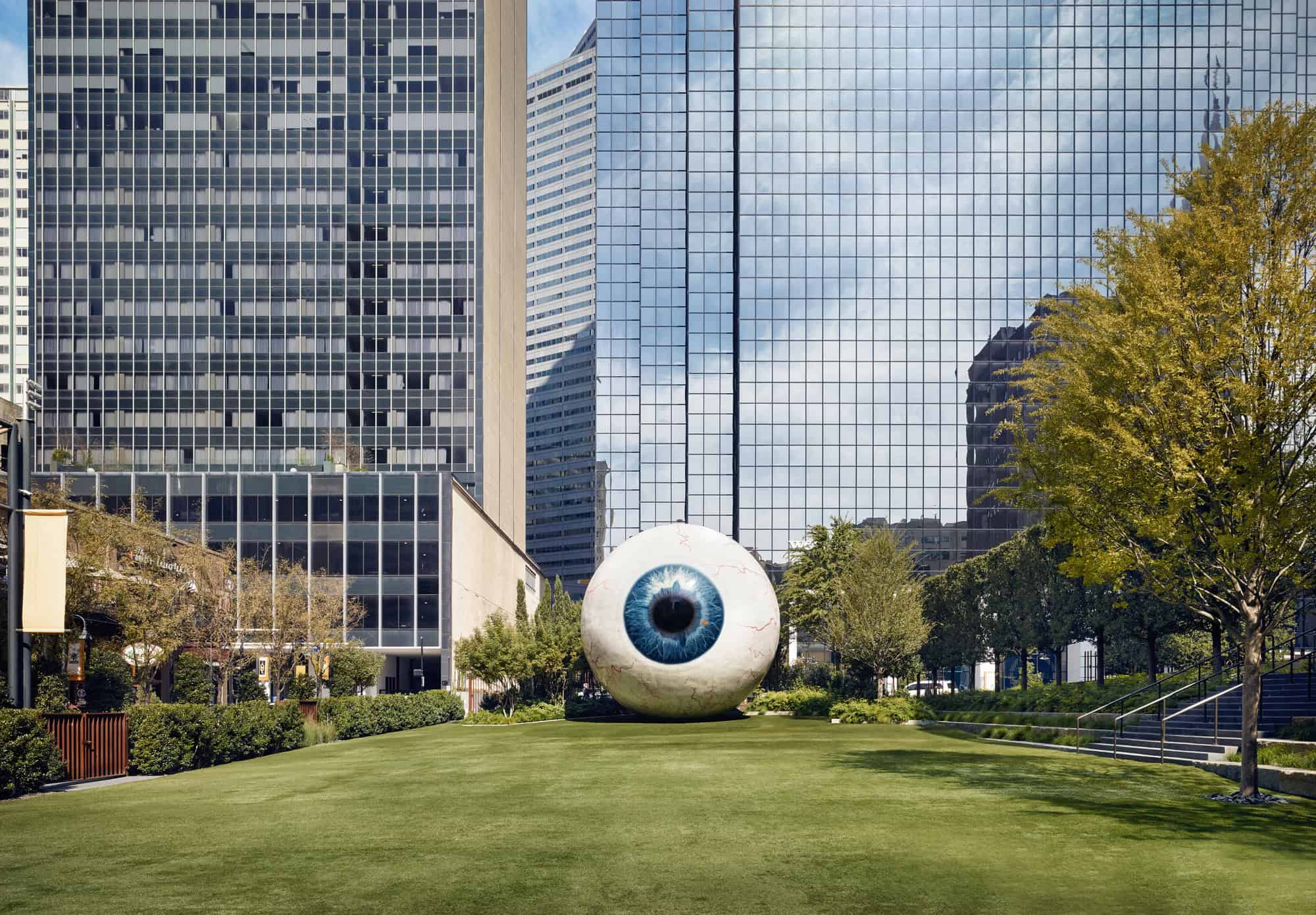 Eyeball sculpture with building in the background and green space