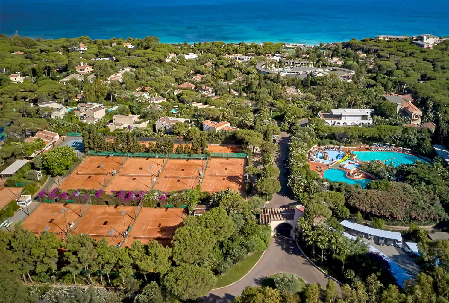 Tennis court on a tropical island, showing a beach in the distance.